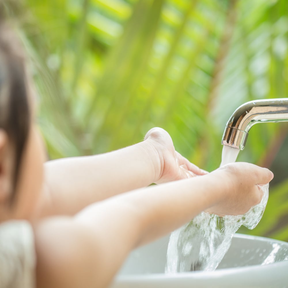 Small girl washing hands in clean water